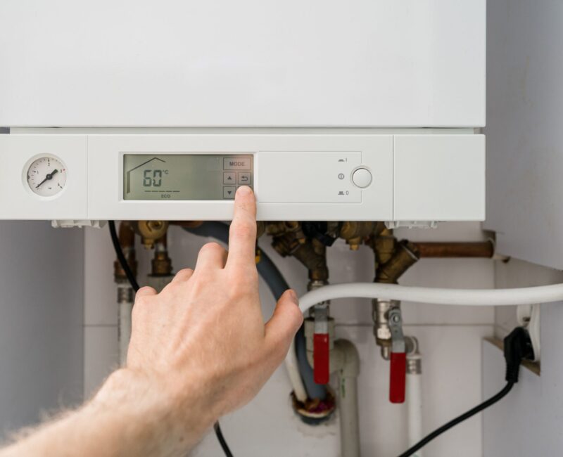 Man,Is,Press,Button,On,Gas,Boiler,With,Digital,Control